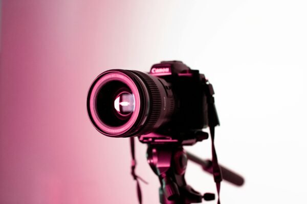 Canon DSLR camera with lens on tripod in studio lighting, perfect for photography enthusiasts.