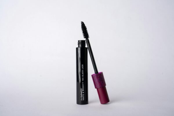Black mascara product on white background with pink glitter cap.