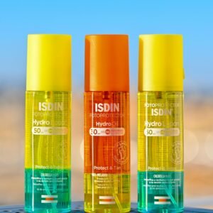 Three colorful ISDIN sun protection bottles against a blurred background, showcasing vibrant packaging.