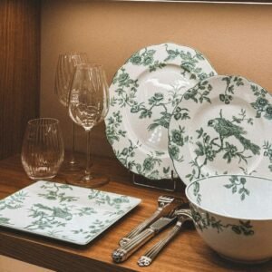 A stylish arrangement of floral porcelain, glassware, and teapots on modern wooden shelves.