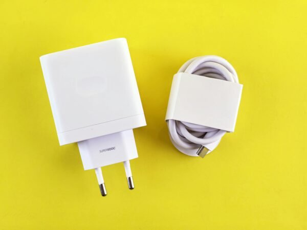 White SuperVOOC charger and cable on a bright yellow background, showcasing minimalist design.