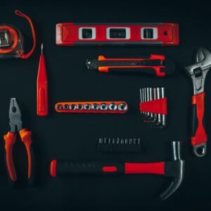 Top view arrangement of various repair tools including pliers hammer screwdriver and tape measure placed on black table