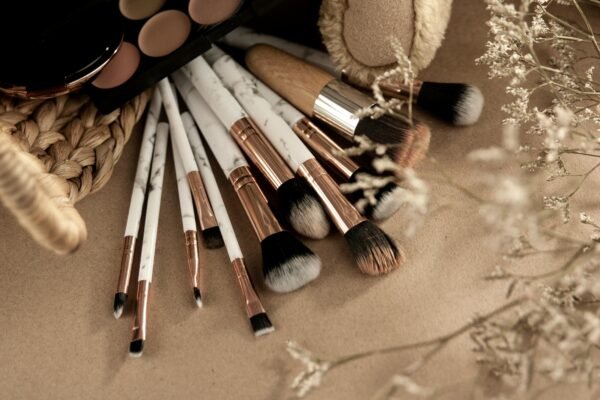 From above of makeup brushes with eyeshadows on beige background with branches of dried plants